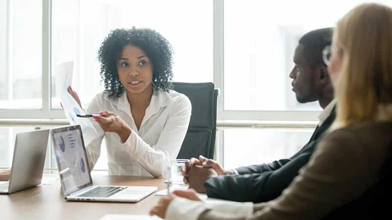 Mitarbeiter diskutieren über gedrucktes Tabellenblatt Mitarbeiter diskutieren über gedrucktes Tabellenblatt