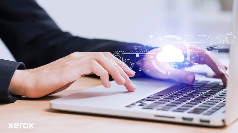 Xerox® Workplace Cloud und Suite: Cloud-Konnektivität Zu sehen sind die Hände einer Person, die auf einer Laptoptastatur tippt. Über das Bild sind ein leuchtendes Wolkensymbol und Netzwerkverbindungen gelegt, die Cloud-Konnektivität und digitale Arbeitsabläufe symbolisieren.