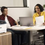 Xerox® C410 Farbdrucker am Arbeitsplatz Zwei Personen im Büro neben dem Farbdrucker Xerox® C410